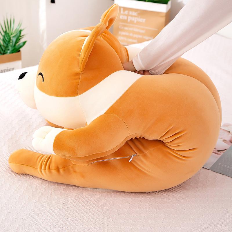 Happy sleeping corgi plushie pillow resting on cozy bedspread